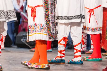 Close up of legs of young Romanian dancers perform a folk dance in traditional folkloric costume....