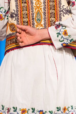 Young Romanian dancer hold hand on his back while perform a folk dance in traditional folkloric costume. Folklore of Romaniaの写真素材