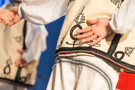 Young Romanian dancer hold hand on his back while perform a folk dance in traditional folkloric costume. Folklore of Romaniaの写真素材