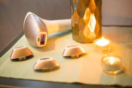Laser epilator on table with three extensions and two candlesの写真素材