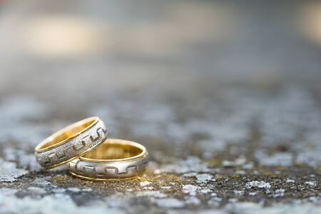 Close up of two wedding rings on concrete with blurred backgroundの写真素材