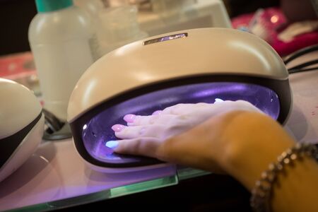 Women hand in polish drying machine in nail salonの写真素材