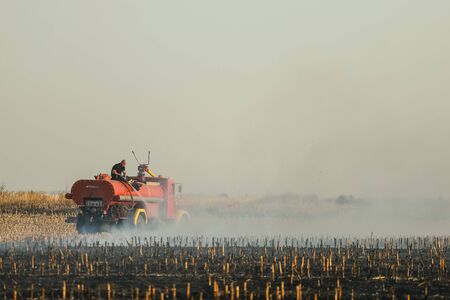 Pancevo, Serbia - October 24, 2019: Firefighters extinguishing fire on burning corn field.の写真素材