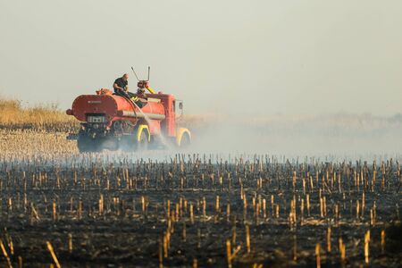 Pancevo, Serbia - October 24, 2019: Firefighters extinguishing fire on burning corn field.の写真素材