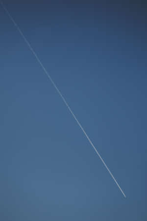 Flying airplane trail in a clear skyの写真素材