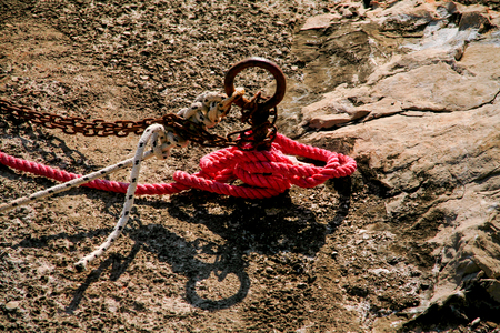 Red fisherman rope tied to a hook, close up. Cleat and rope, yacht detail. Yachting concept. Close up of boat rope tied on figure eight cleat hitch rope on the ship.の写真素材