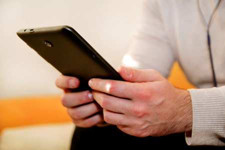 Human hands holding a tablet and using or online social network at home office. Business man use contact information from tablet.の写真素材