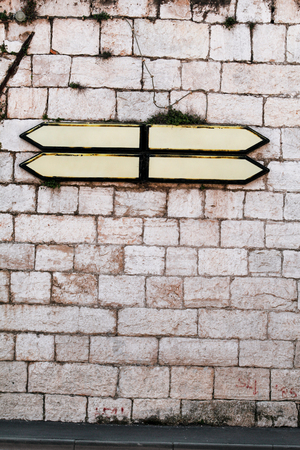 Roadmap signs and guidepost with a stone wall in background. Direction Signboard on the old stone wall. Background and Texture for text or image.の写真素材
