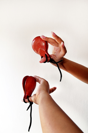 Spanish castanets in the hands on white background, close up. Percussion instrument used in flamenco, sevillanas dance in Spain, isolated, close up. Hands detail of flamenco dancer with castanets.の写真素材