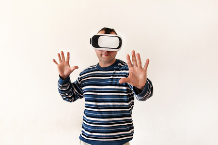 Man wearing and playing mobile game app on device virtual reality glasses on white background. Man...