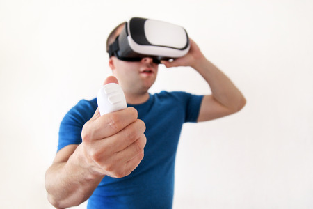Man wearing and playing mobile game app on device virtual reality glasses on white background. Man action and using in virtual headset, VR box for use with smart phone. Contemporary technology conceptの写真素材