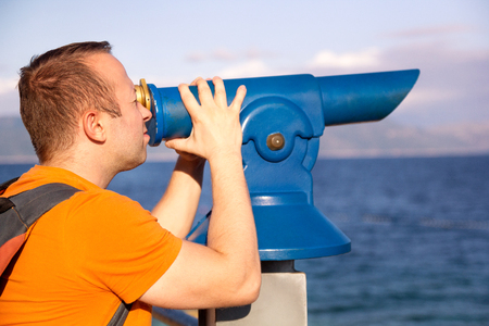 Man tourist and traveler using, watches and looks natural environment in telescope telescope at beach of Adriatic Sea, Mediterranean / Panorama and view of sea and sky.の写真素材