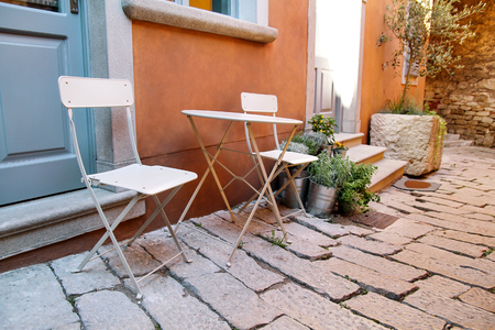 Chairs and a table in garden. Steel chairs and a table standing in a beautiful garden at sunny day. Patio furniture. A set of chairs and a small table set outdoor.の写真素材