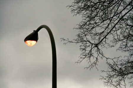 Illuminated light electric lamp on street in twilight time / Lamp light on pole on twilight sky background view. Urban city scene / Energy and power.の写真素材