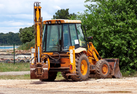 Yellow excavator, bulldozer machine and worker tractor. Road works. Road machinery at construction site. Road company and building machines for construction. Industry, renovation and infrastructure.の写真素材