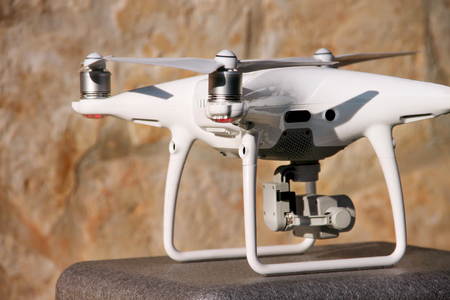 White quadcopter Drone with 4K digital camera on stand is ready for take off to fly in air to take...