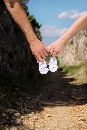 Pregnant woman and man holding baby shoes in hands. Future mom and dad, parents is holding little newborn baby shoes. Birth expectation concept. Waiting of baby. Pregnant woman, pregnancy, motherhood.の写真素材