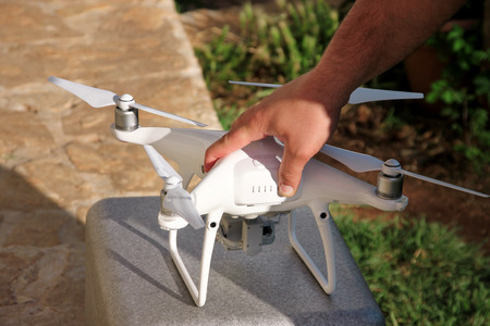Man is holding a drone in hand and using of new technology. White quad copter Drone and photographer...