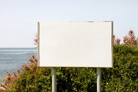 Blank advertising billboard display and table, sea in background. Advertising agencies. Billboard with copy space for text message or content, outdoor advertising mock up, public information board.の写真素材