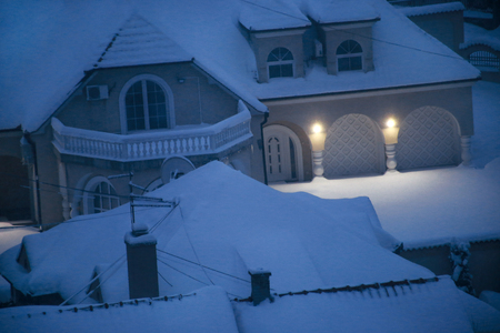 Beautiful winter view of houses and buildings with roofs covered with heavy snow.の写真素材