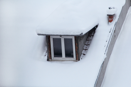 Beautiful winter view of houses and buildings with roofs covered with heavy snowの写真素材