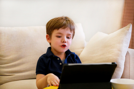 Child using tablet pc on bed at home.の写真素材