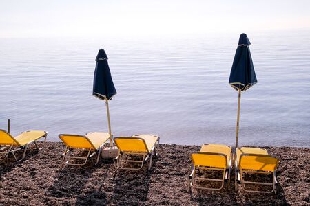 Early morning on sandy beach without people with empty chaise loungesの写真素材