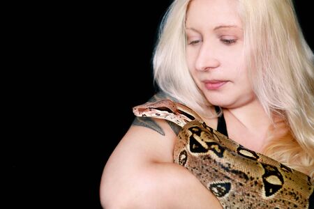 Portrait of girl with Boa constrictor snake. Beautiful woman holds snake in hands and posing in front of camera.の写真素材