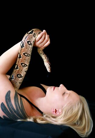 Portrait of girl with Boa constrictor snake. Beautiful woman holds snake in hands and posing in front of camera.の写真素材