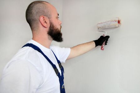 Construction worker doing finish renovation at apartment. Professional painter contractor using...