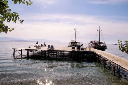 Tourist boat cruiser in small marina on sea and beautiful beach, waiting tourists for ship is sailing out of port for next tourist tour. Anchored cruise ship in harbor. Summer season, travel, holiday.の写真素材