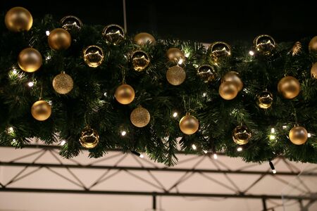 Traditional decorated Christmas baubles on wreath made of green fir or spruce branches and glowing garland outdoors.の写真素材