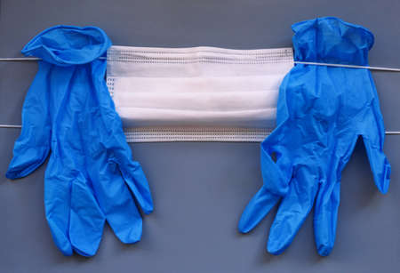 Pair of medical blue latex protective glove and white mask on gray background. Protection equipment...