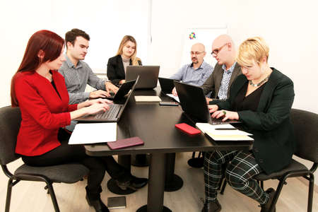 Business men and women at the meeting. Corporate group. Full concentration at work. Group of business people working and communicating while sitting at office desk together with colleagues sitting.の写真素材