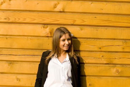 Girl standing in front of a wooden houseの写真素材