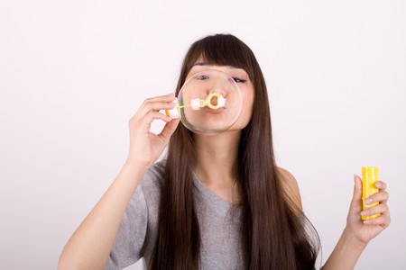 Girl blowing soap bubbles in studio