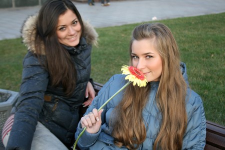 Two happy girls sitting on bench in parkの写真素材