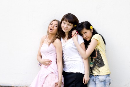 Three female friends standing in front of a white wallの写真素材