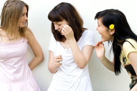 Three female friends standing in front of a white wallの写真素材