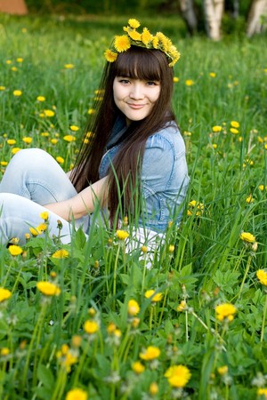 Girl sitting among dandelionsの写真素材