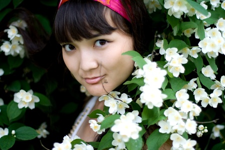 Closeup portrait of a beautiful girl standing among flowersの写真素材