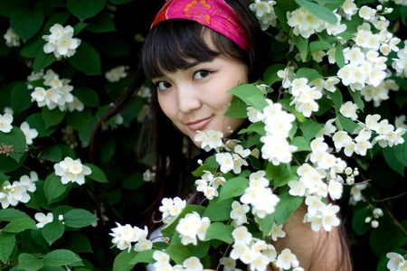 Closeup portrait of a beautiful girl standing among flowersの写真素材