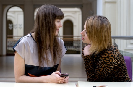 Two female friends sitting in a cafeの写真素材
