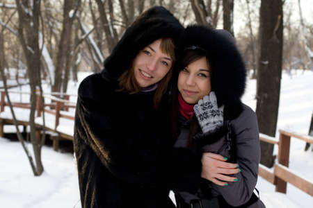 Two female friends walking in park in winterの写真素材