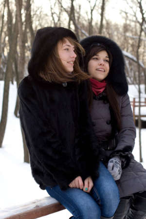 Two female friends walking in park in winterの写真素材