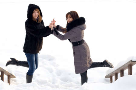 Two female friends walking in park in winterの写真素材