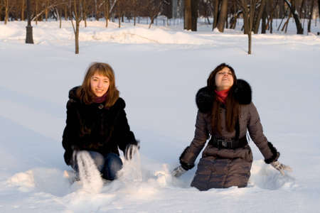 Two female friends walking in park in winterの写真素材