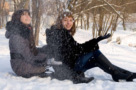 Two female friends walking in park in winterの写真素材