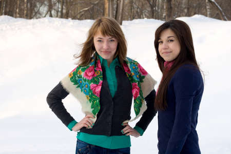 Two female friends walking in park in winterの写真素材