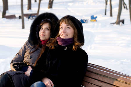 Two female friends walking in park in winterの写真素材